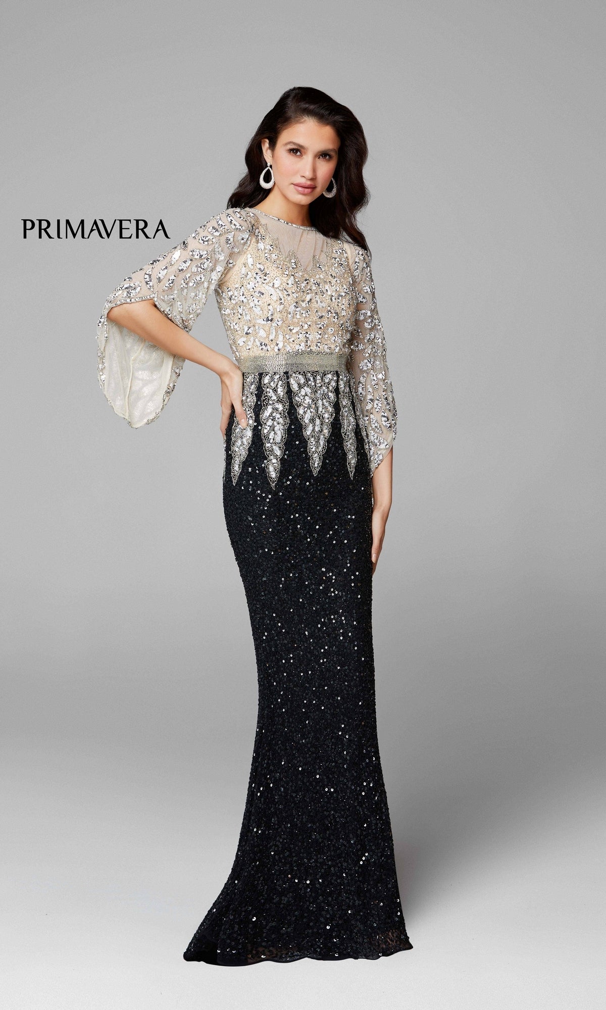 A woman models the Bell-Sleeve Long Beaded Evening Gown 1424 in black and silver, featuring flared sleeves, set against a plain light gray background with “PRIMAVERA” on the left.